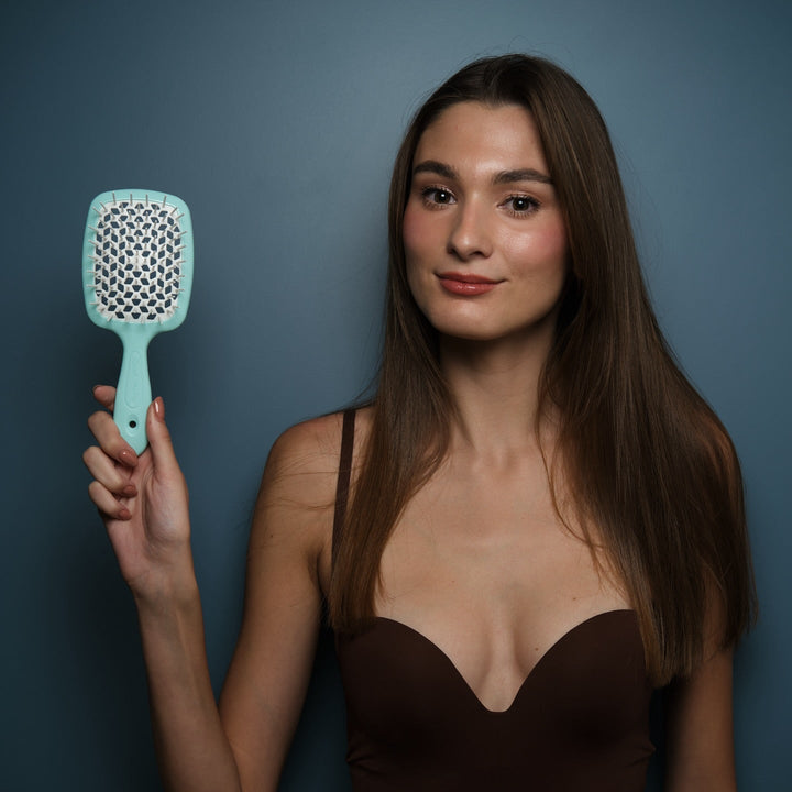 Woman holding a teal hairbrush against a blue background