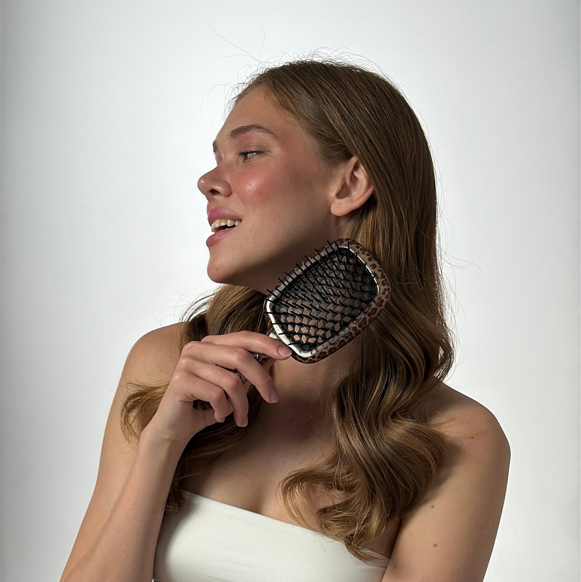 Woman holding a hairbrush against a plain background